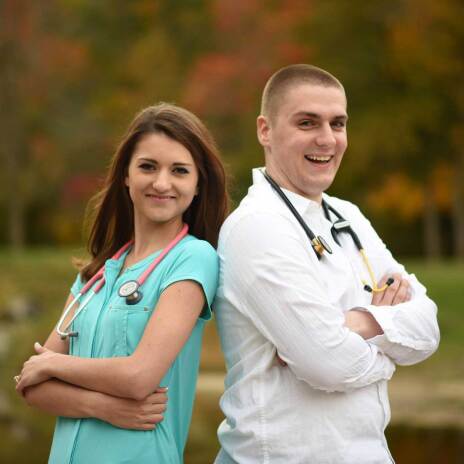 Fiance with husband to be standing shoulder to shoulder with stethoscopes smiling at the camera