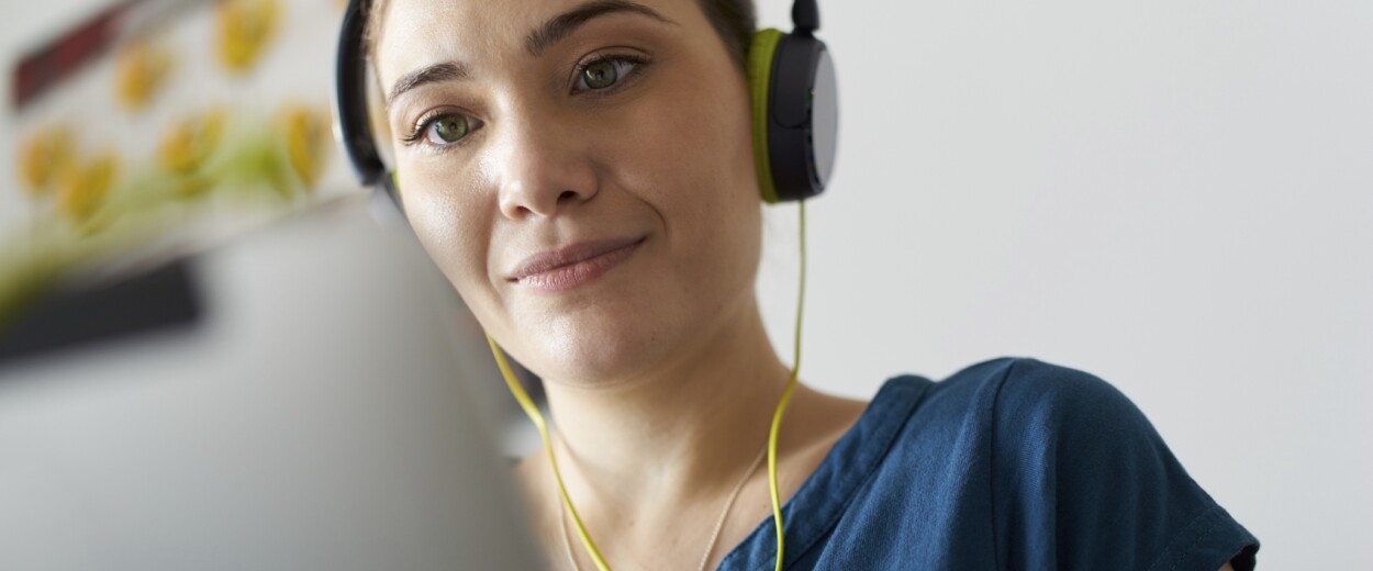 Woman with headphone on looking at laptop