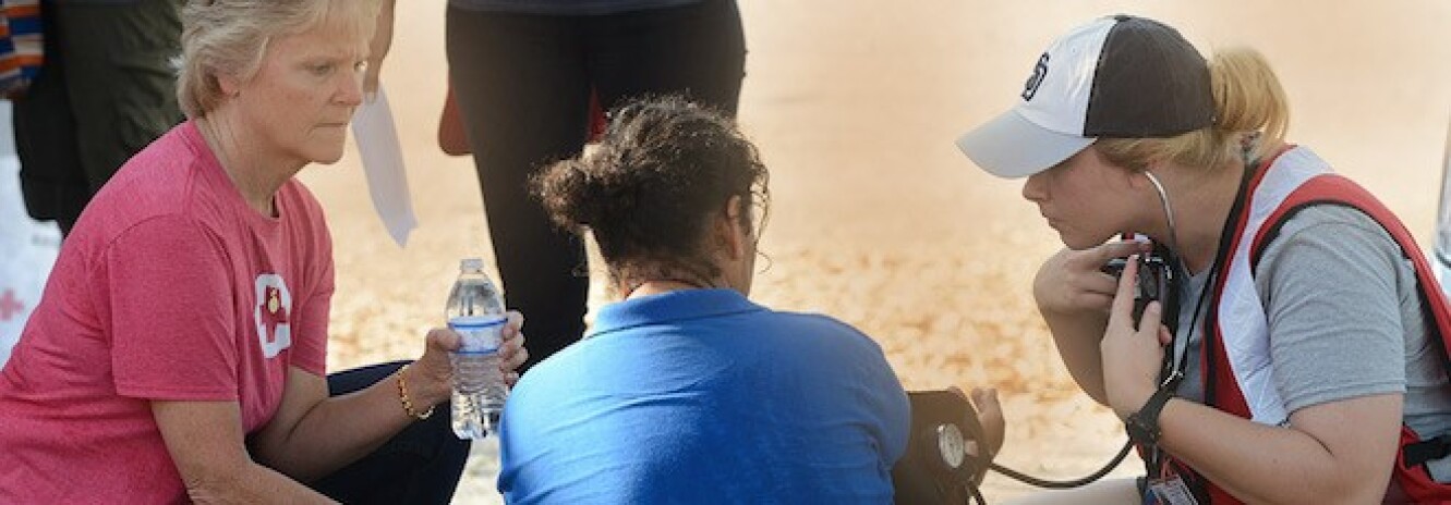 Female nurse taking the vitals of a female runner on the ground