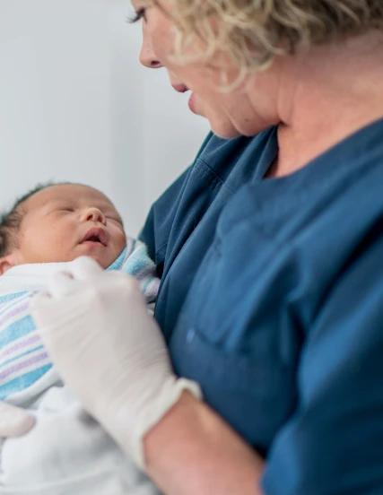 A certified nurse midwife holds a newborn baby