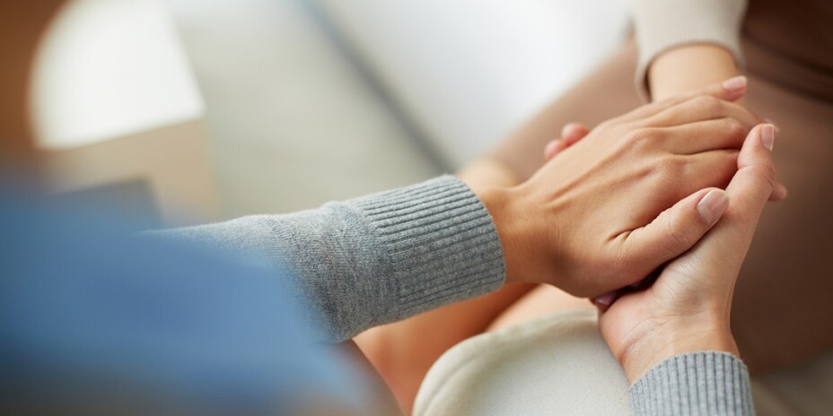 Two sets of hands clasped together in a gesture of comfort