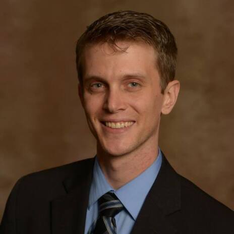 Headshot of male in suit and tie smiling at camera