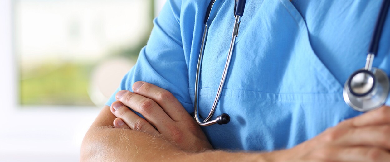 Male nurse in scrubs with arms crossed