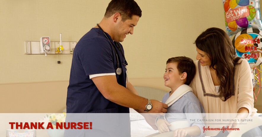 Male nurse in scrubs adjusting sling of smiling young male patient with his mother at his side