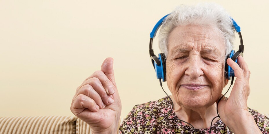 Elderly woman listening to something on blue headphones