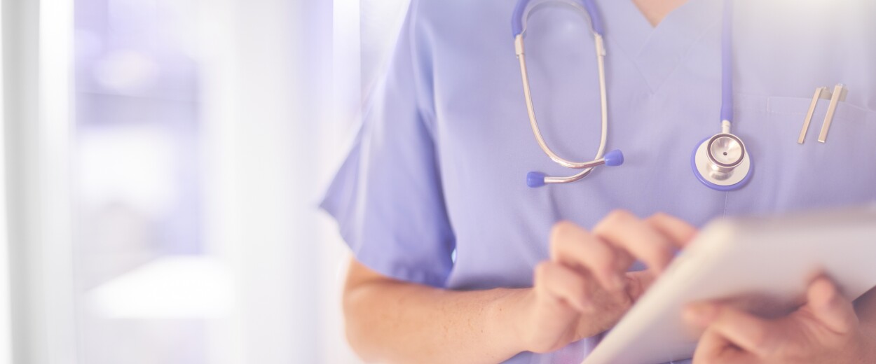 Close up of nurse in scrubs using a tablet