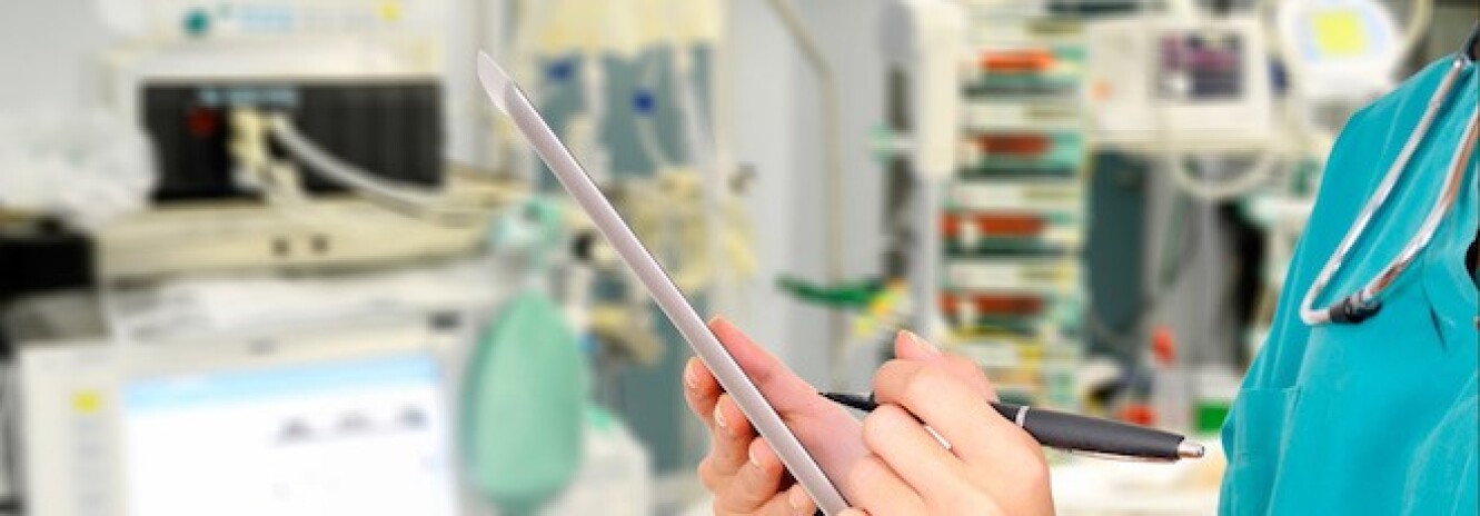 Close up of nurse in scrubs writing on tablet in OR setting