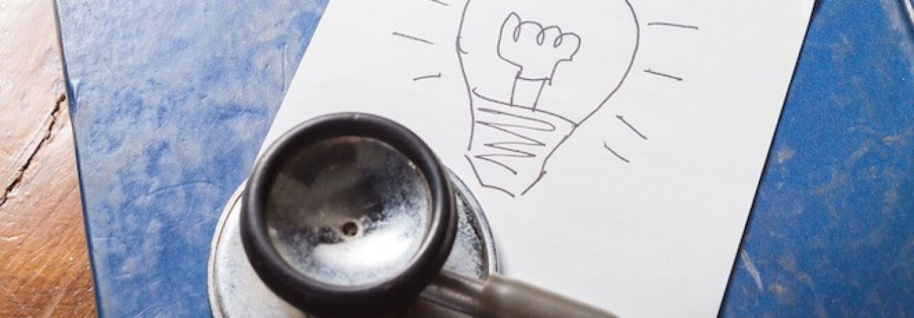 Stethoscope next to piece of paper with lightbulb drawn on it