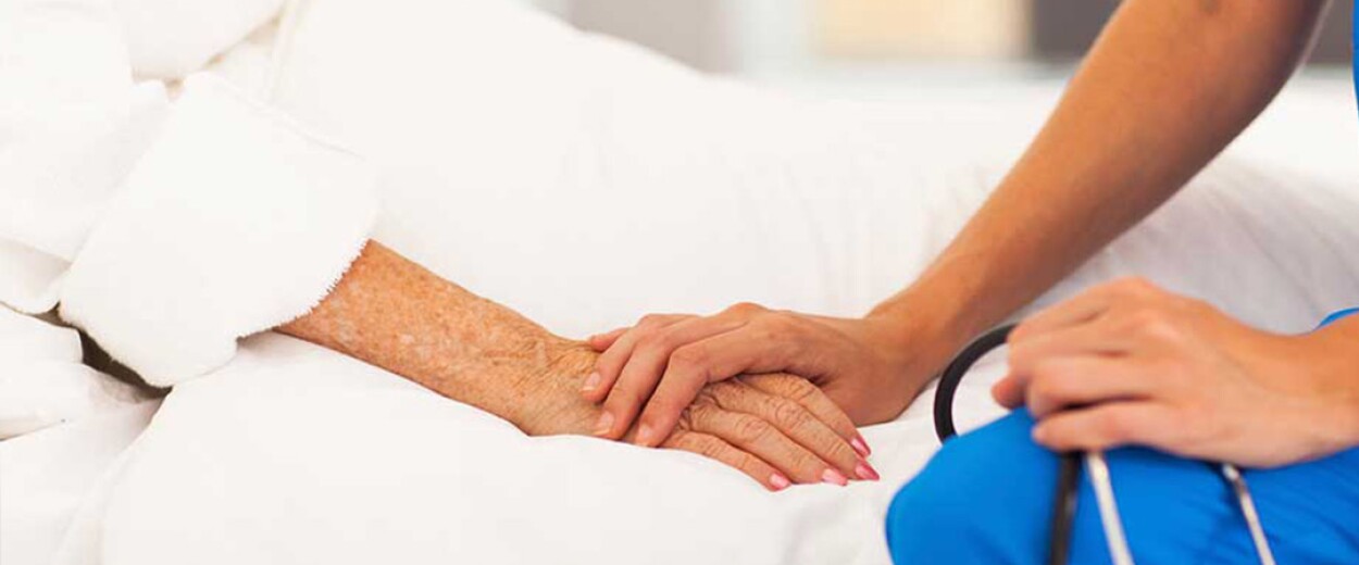 Nurse offering a caring hand to a patient at her bedside