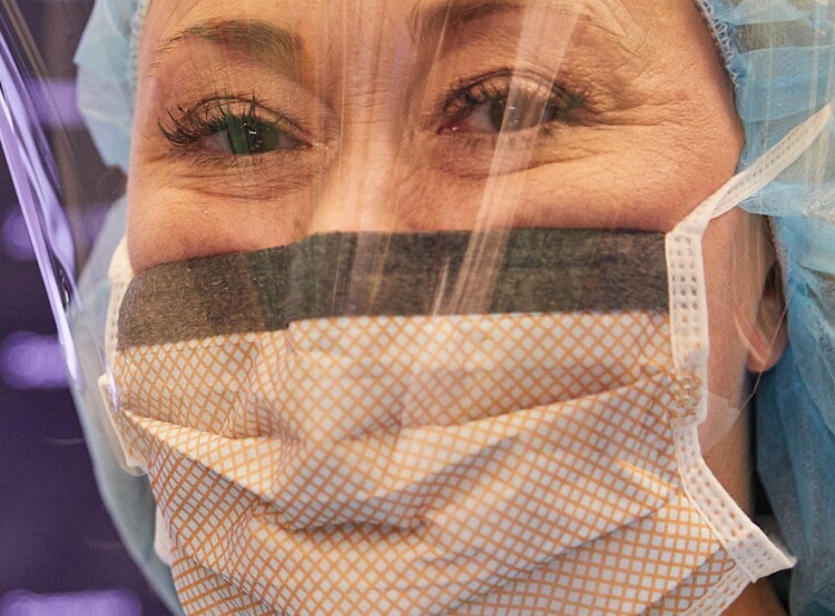 Close-up of a female nurse in scrubs, face mask, and face shield