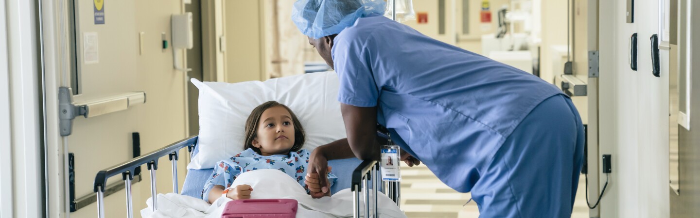 Doctor holding hand of girl in hospital gurney