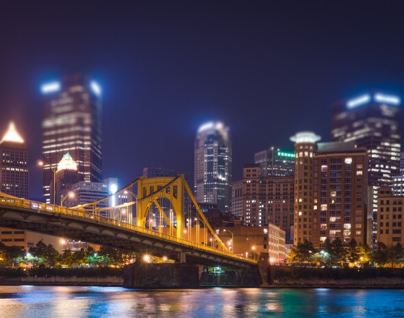 Lit up bridge and skyline reflecting light onto the water at night