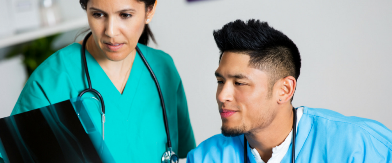 Male and female nurse in full scrubs looking at an X-ray