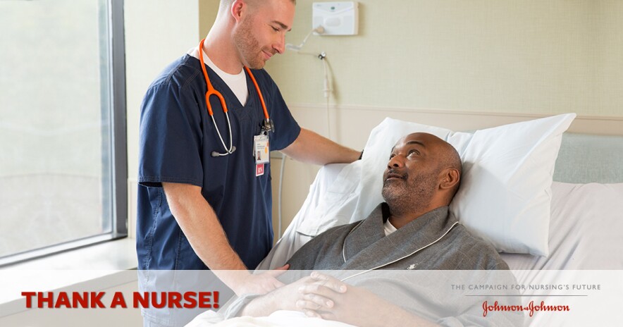 Male nurse in scrubs smiling and talking to male patient in hospital bed
