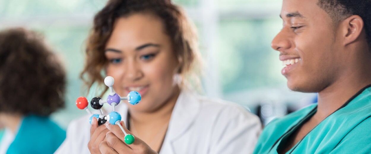 Two nursing students looking at a molecule model that they have made