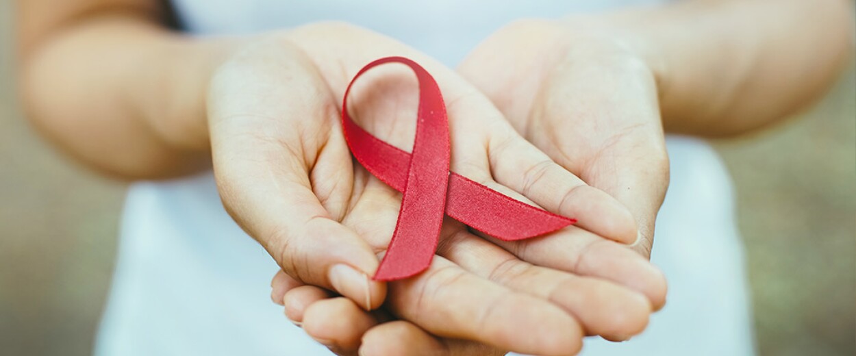 Red ribbon being held in the palm of woman's hand