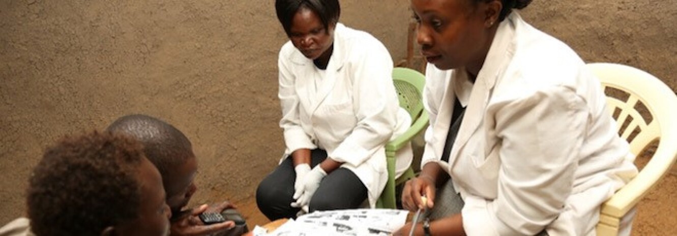 Two female nurses in lab coats talking to a mother and her children